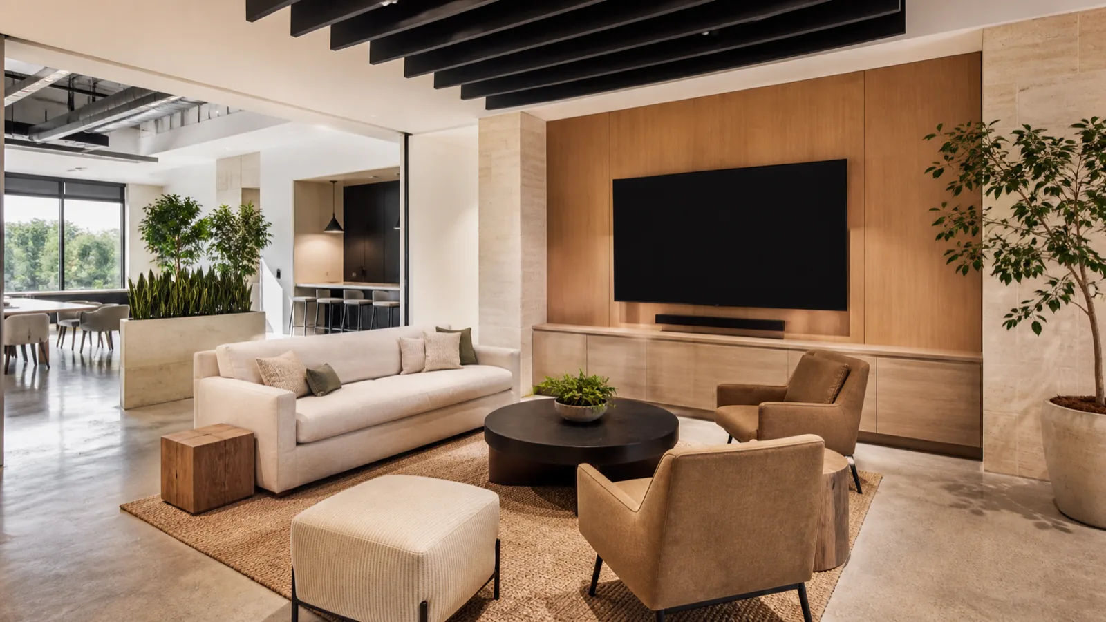 A bright modern collaborative office zone with soft seating, a large blank wall display and acoustic baffles overhead.