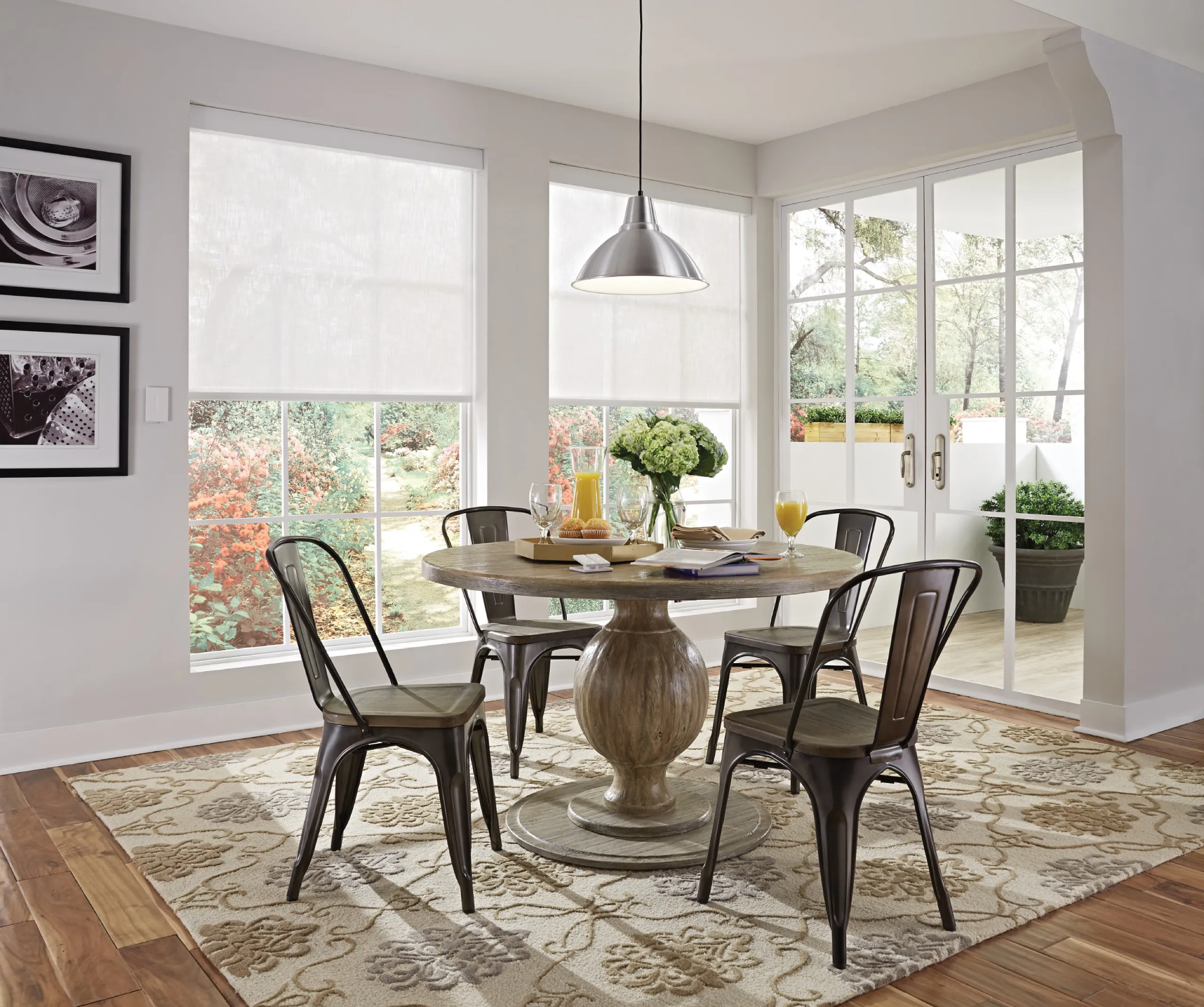 Sunny breakfast nook with round wood table, metal chairs, white roller shades, and French doors to a patio