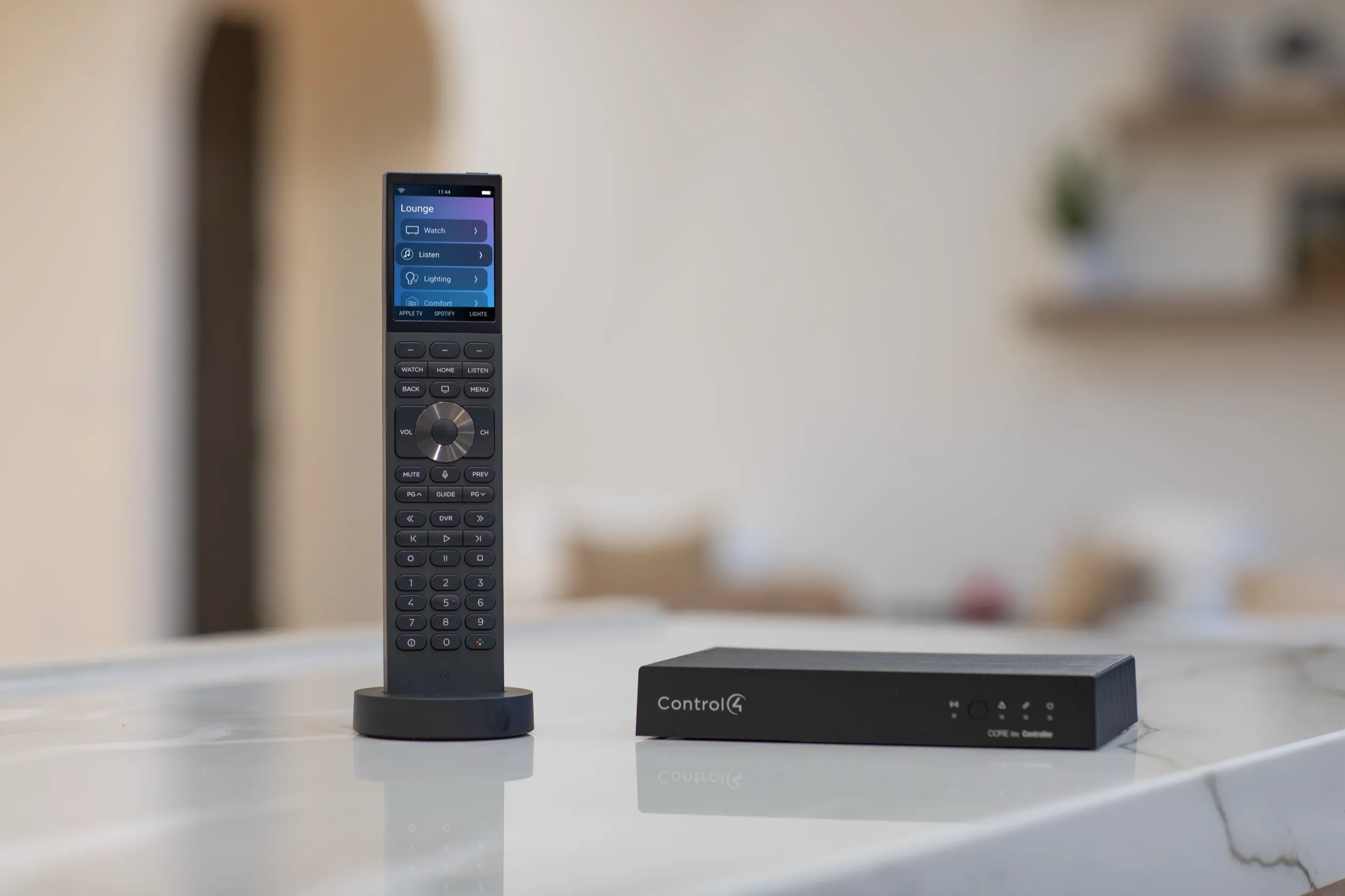 Control4 handheld remote next to a black CORE-HC home controller on a marble counter.