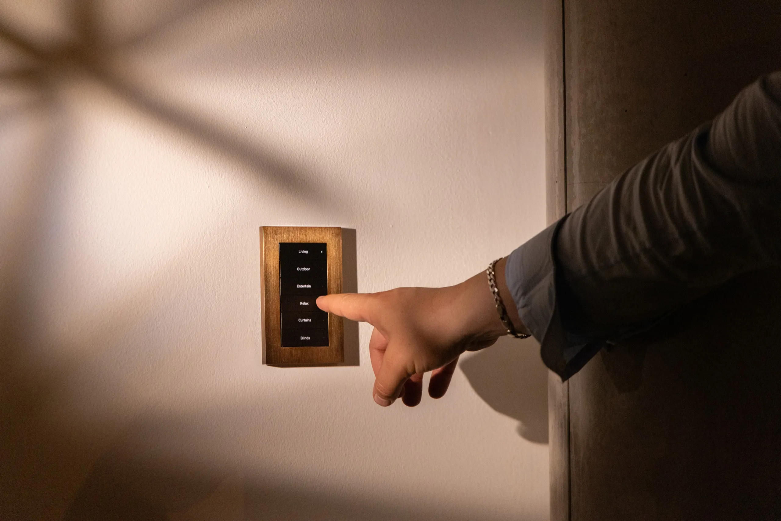 Finger pressing a scene button on a wall keypad — the one-touch handover moment.