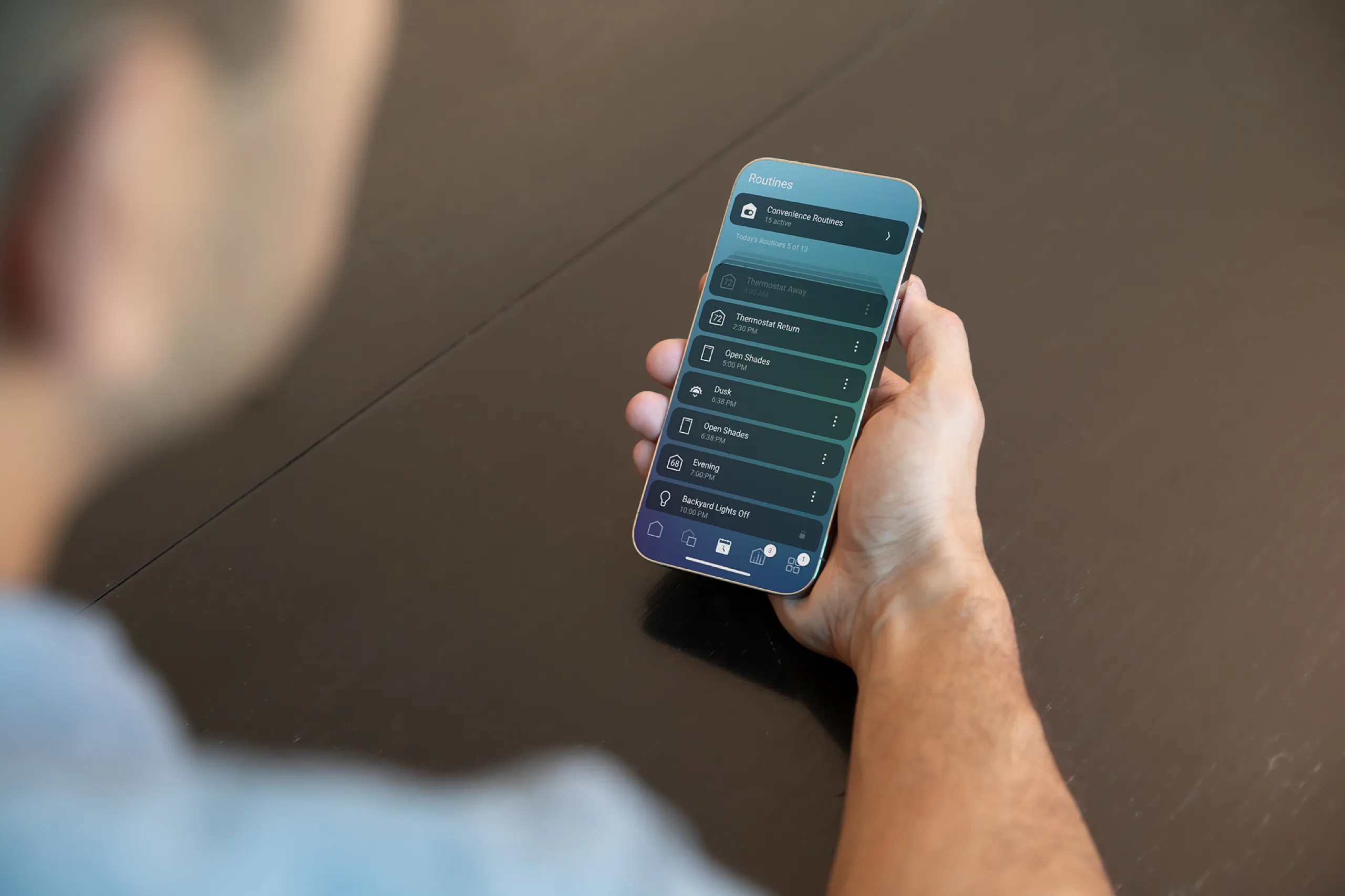 Person holding a phone open to a smart-home routines schedule list.
