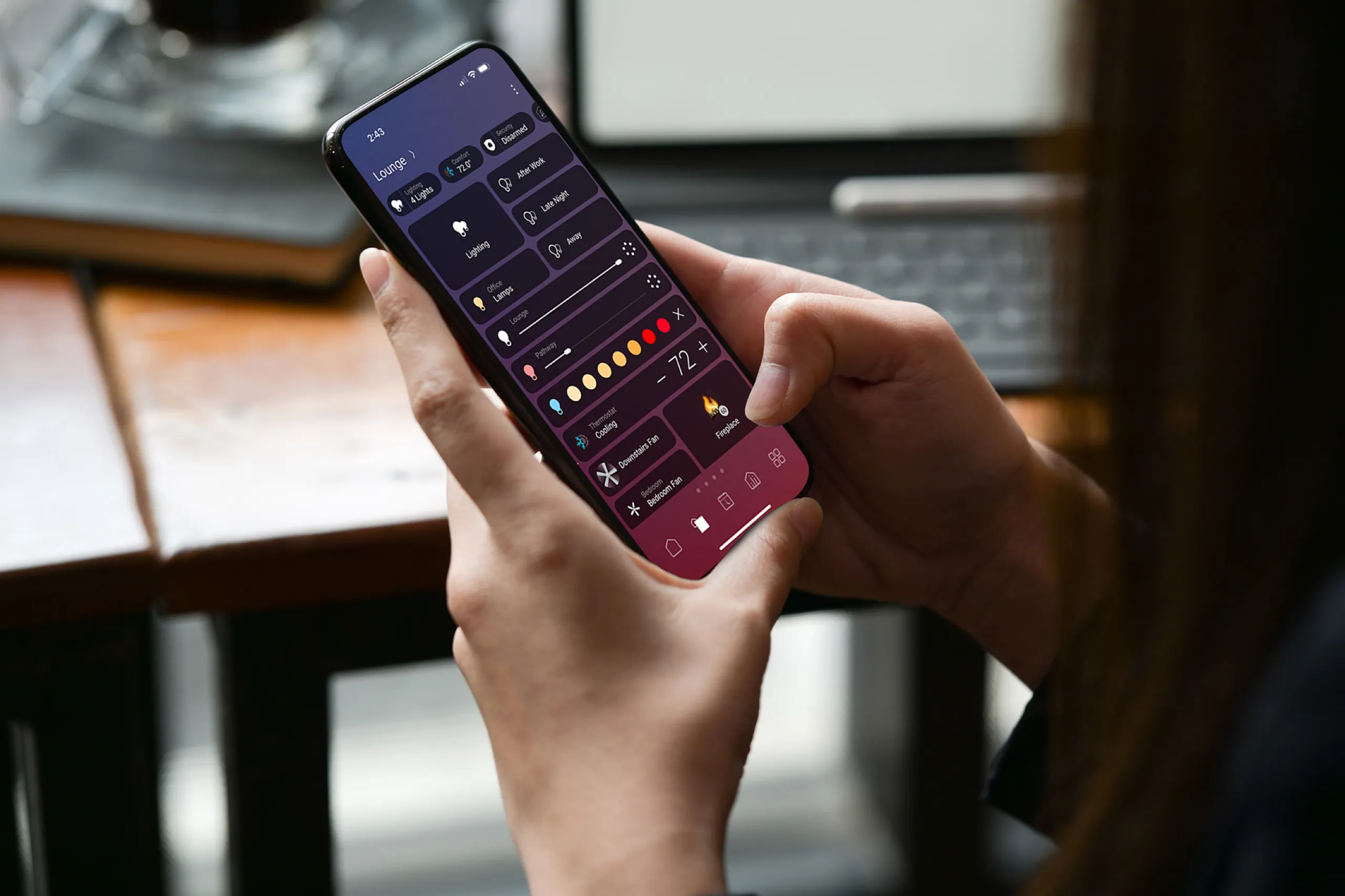 Hands holding a phone with a smart-home app controlling lounge lights and temperature.