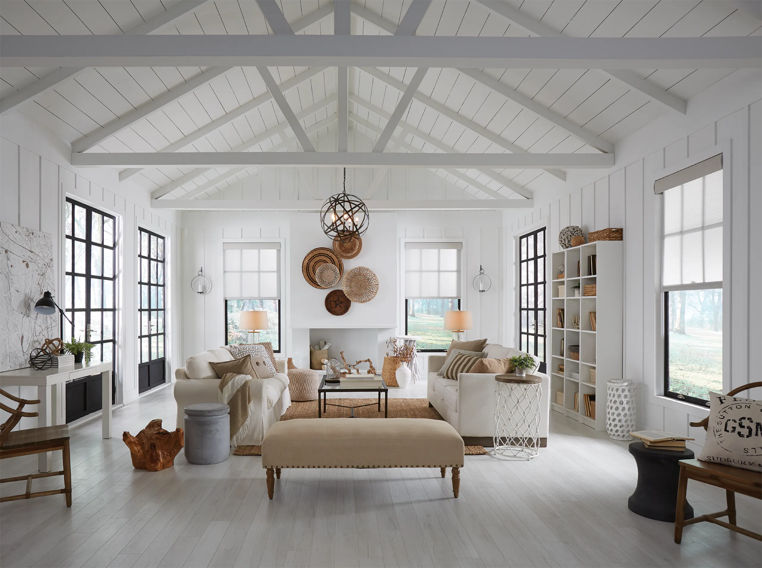 Bright white living room with vaulted ceiling, cream sofas, and light roller shades set at matching mid heights.