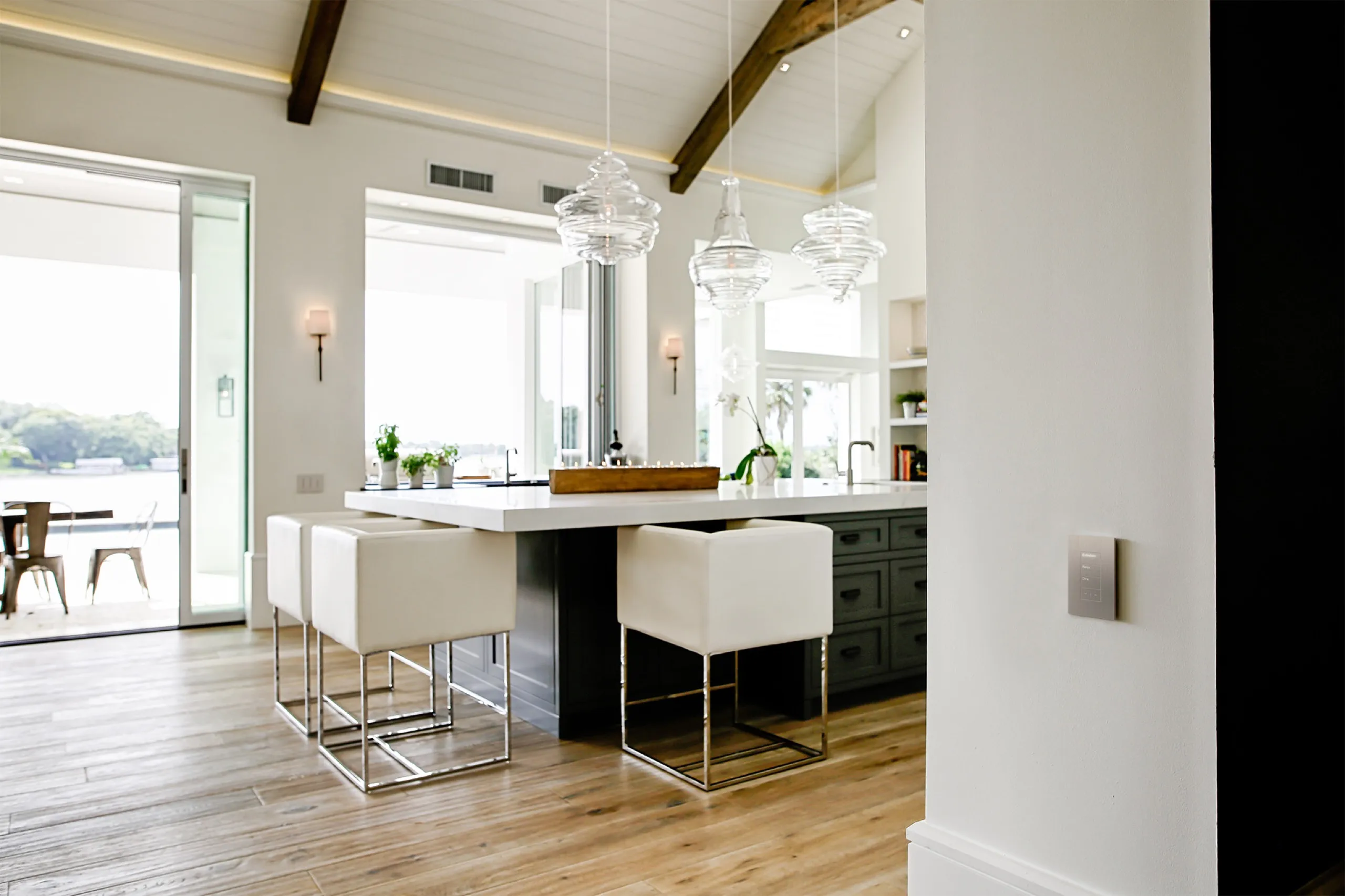 Luxury kitchen island scene with a brushed-metal Lutron Palladiom keypad on the foreground wall.