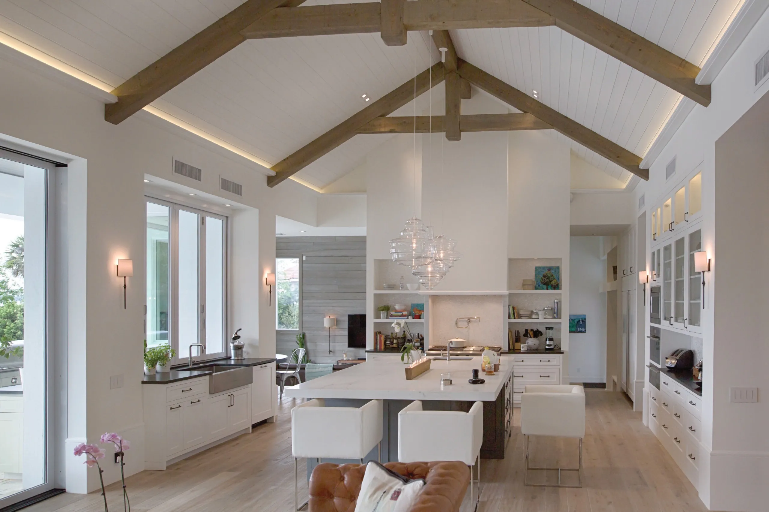 Dimmed luxury kitchen with warm cove lighting, a glass globe chandelier, and vaulted ceiling beyond.