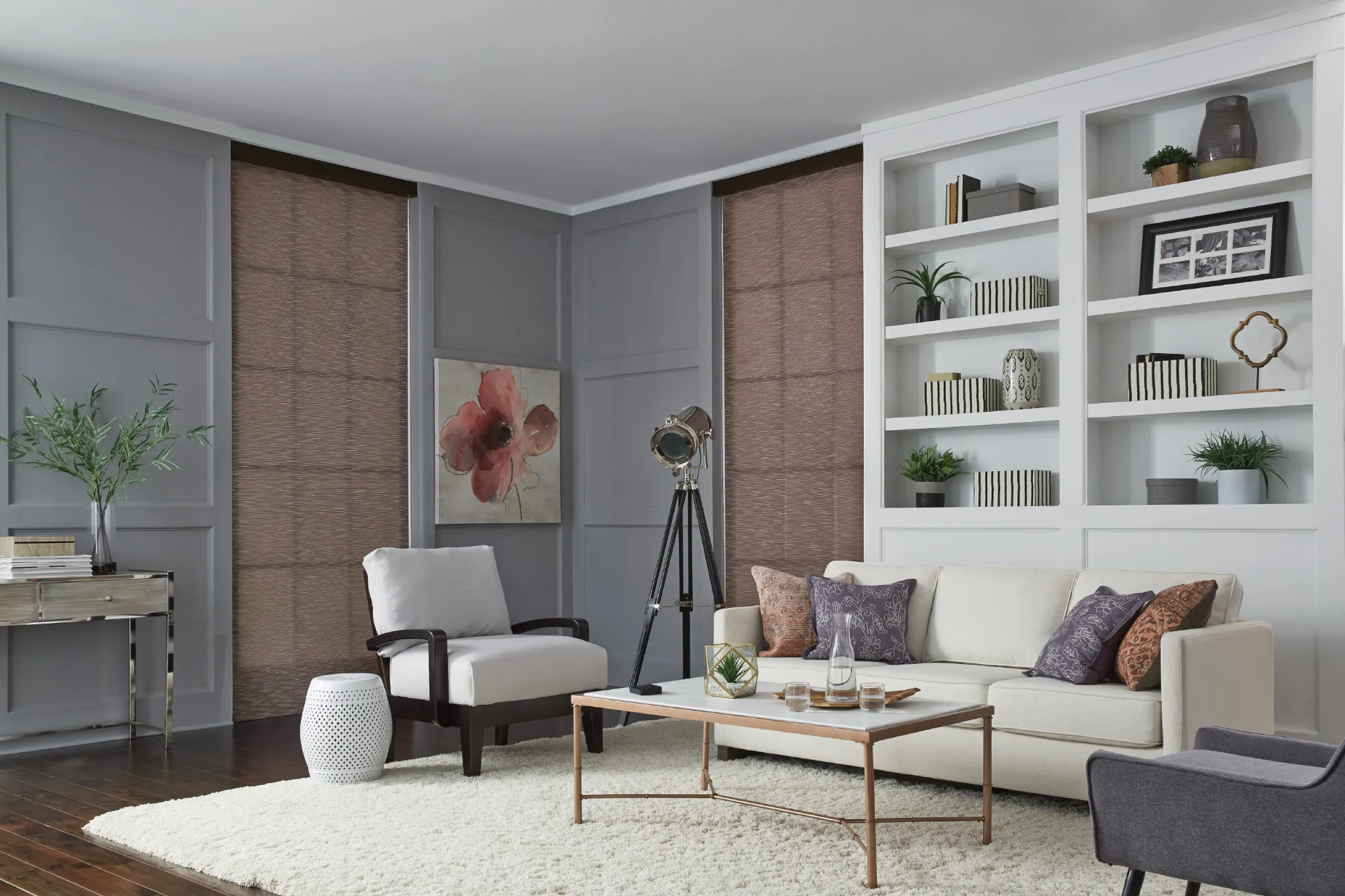 Elegant gray living room with closed brown textured shades, white sofa, and built-in white shelving.