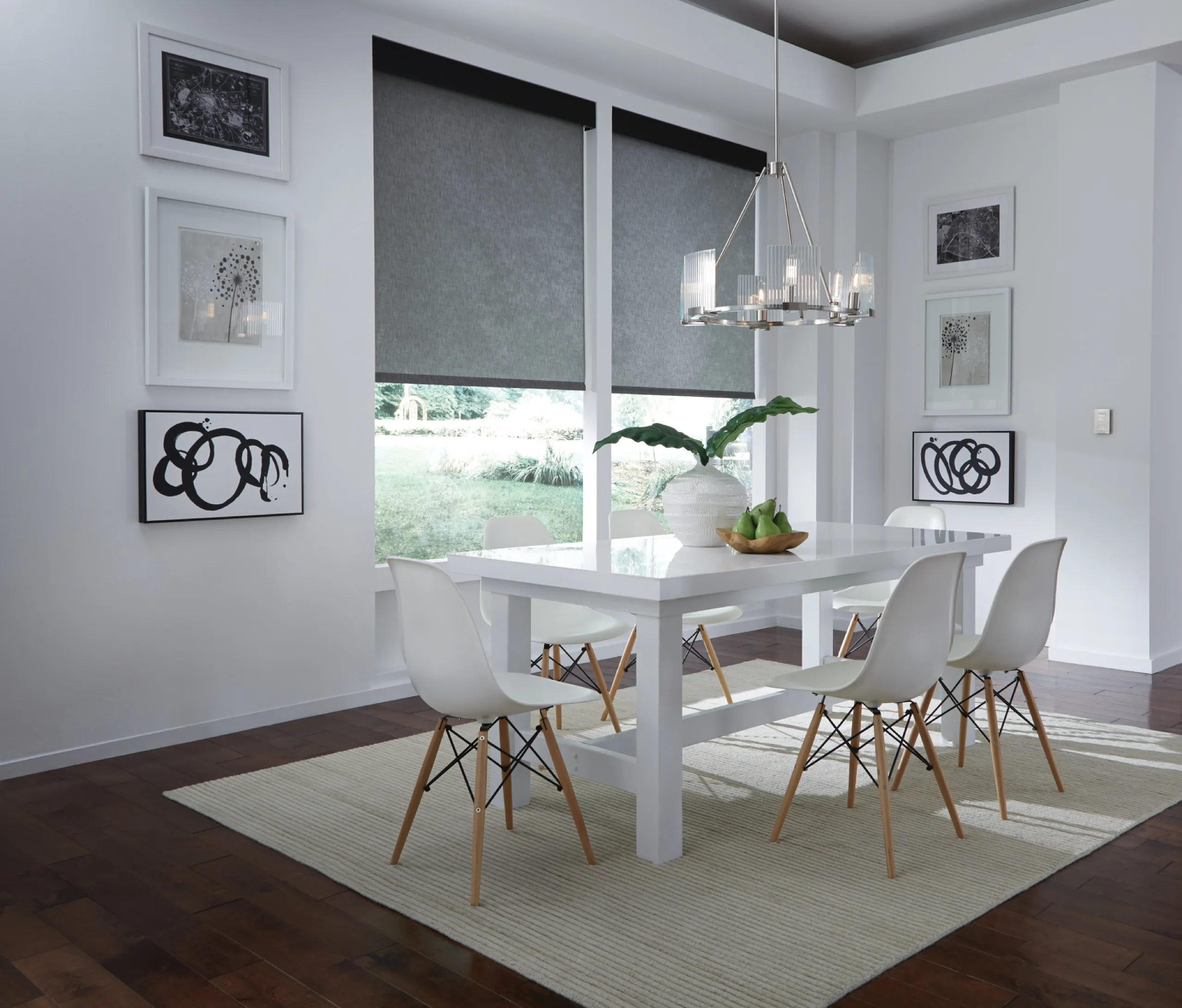 White modern dining room with charcoal roller shades, glossy table, and glass-rod chandelier