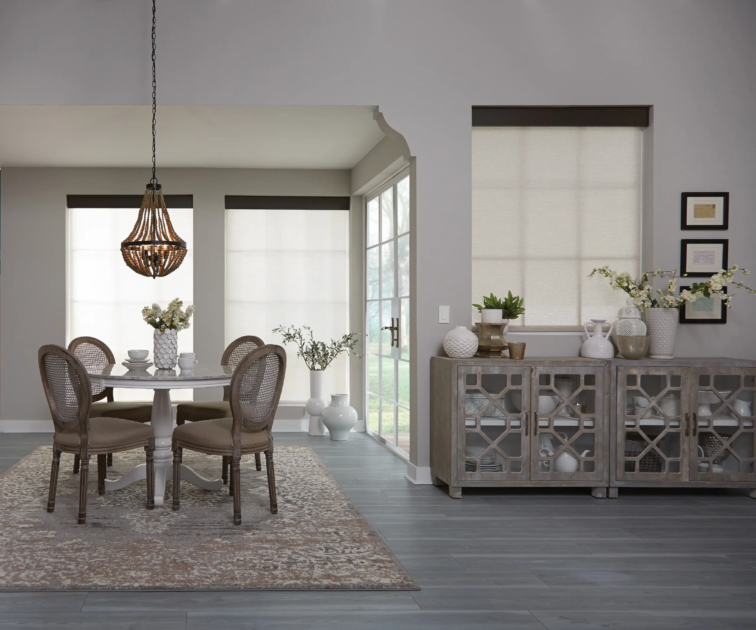 Farmhouse dining room with cream closed roller shades, cane-back chairs, and a gray lattice-door sideboard