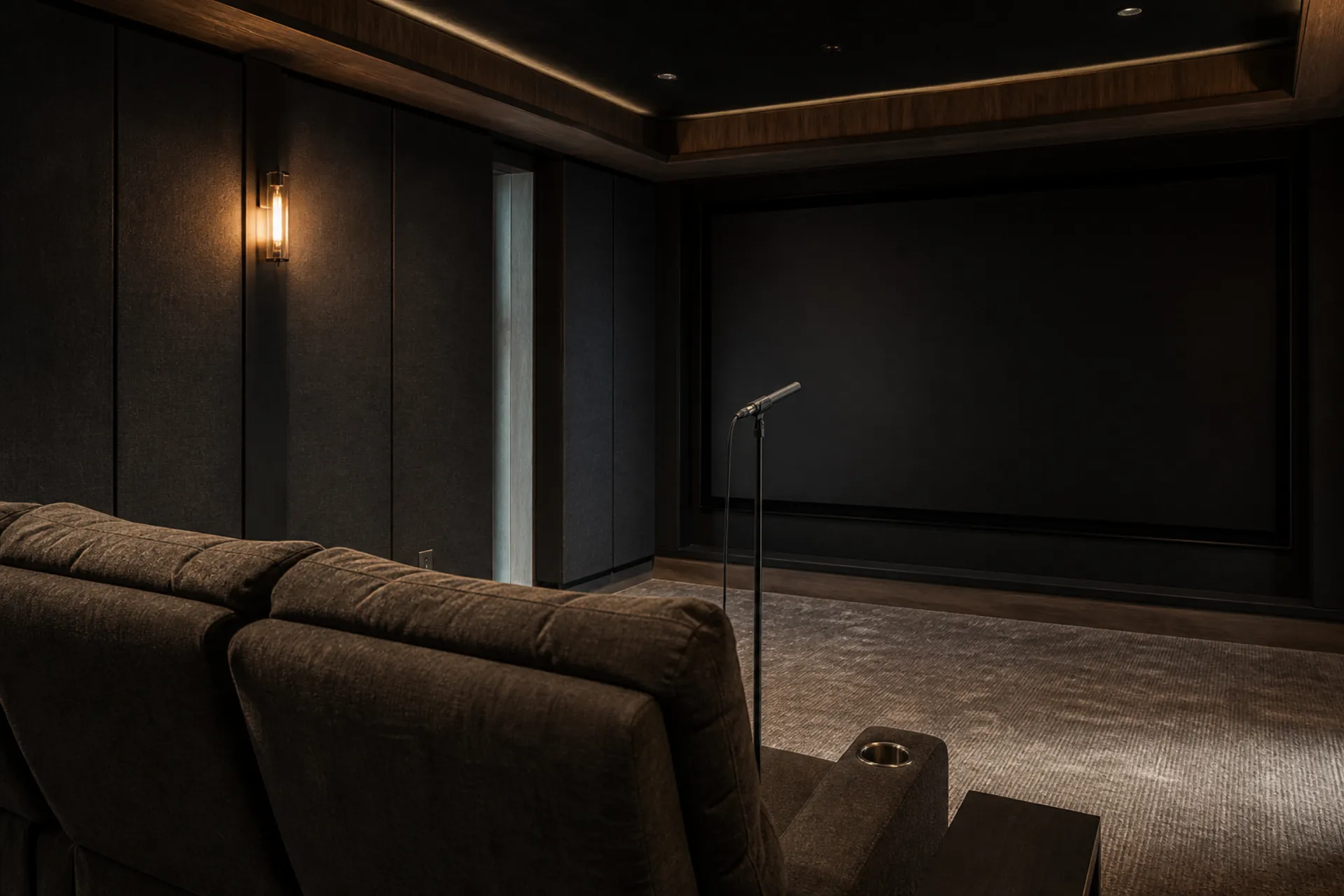 Home theater during calibration, with a measurement microphone on a stand facing a blank projection screen between fabric wall panels.
