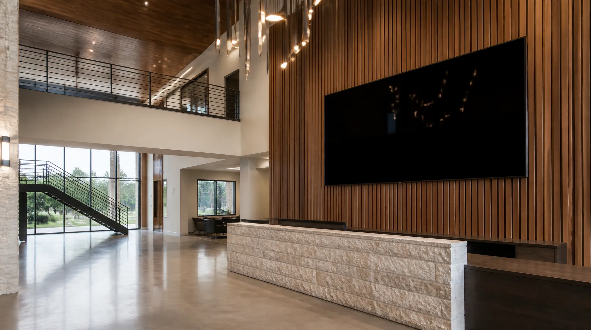 Corporate lobby with a very large display switched off above a walnut reception desk beside full-height glass.